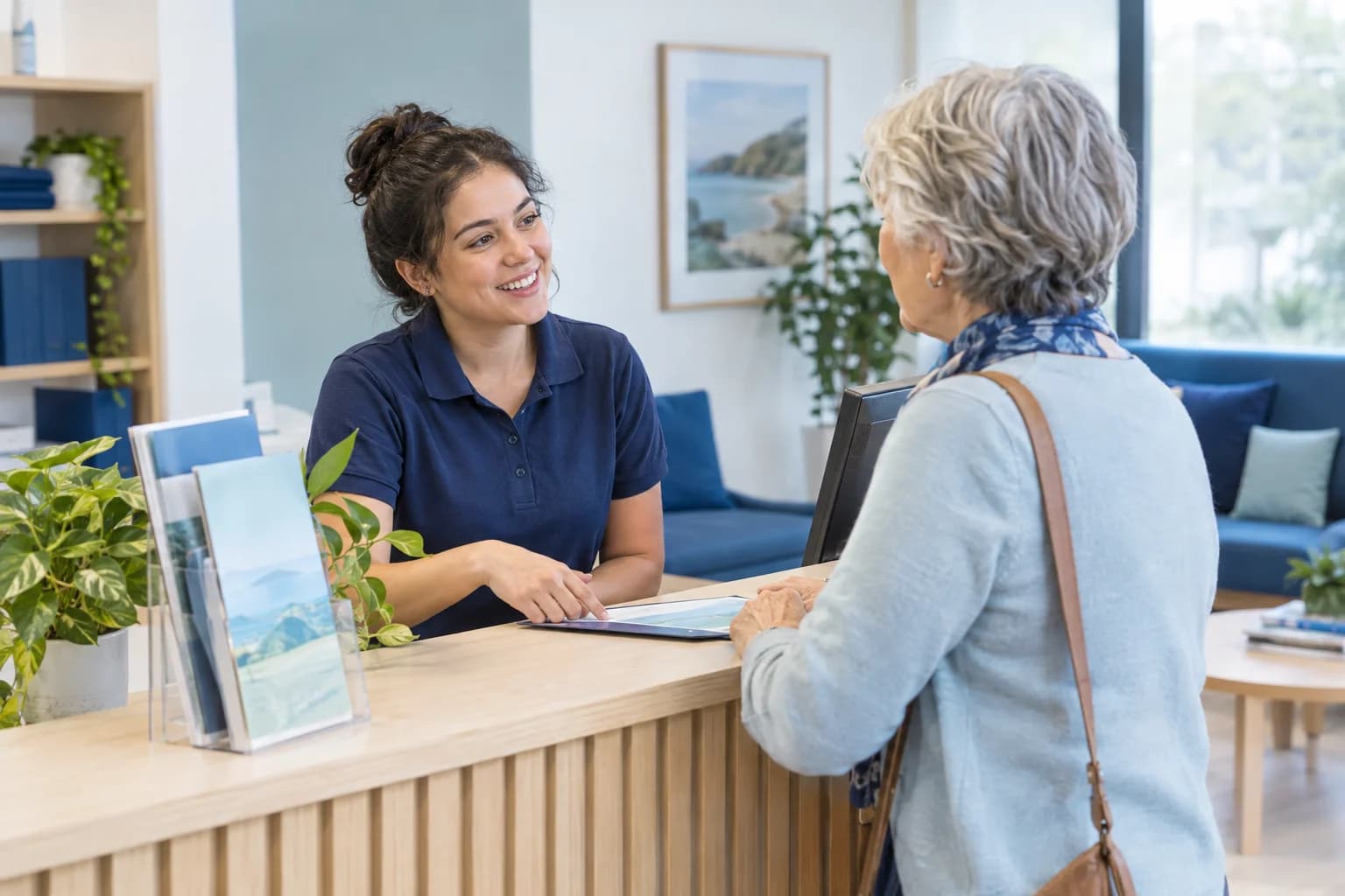 Photo of a receptionist smiling while answering a patient's question at the front desk